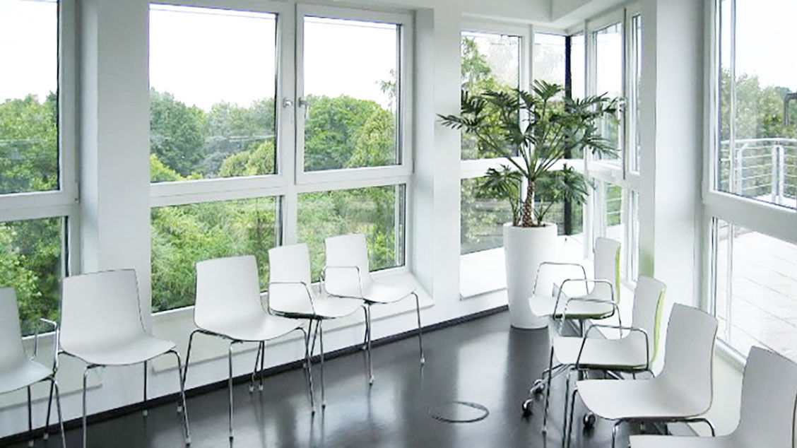 Bild Wartezimmer mit großer Glasfront und weissen Stühlen